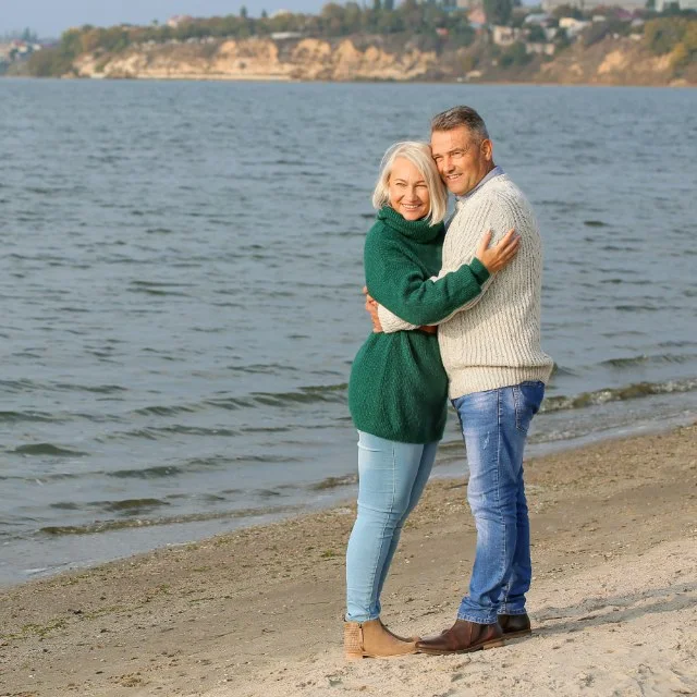 Older couple hugging by the water